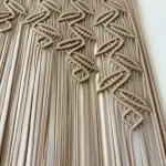 Handmade earthy leaf macrame curtain and large wall hanging by Kemet Vibes hung on a wooden dowel in a sunlit room