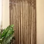 Handmade earthy leaf macrame curtain and large wall hanging by Kemet Vibes hung on a wooden dowel in a sunlit room