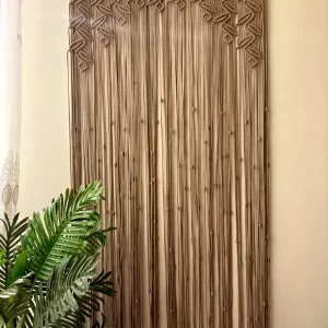 Handmade earthy leaf macrame curtain and large wall hanging by Kemet Vibes hung on a wooden dowel in a sunlit room