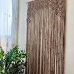 Handmade earthy leaf macrame curtain and large wall hanging by Kemet Vibes hung on a wooden dowel in a sunlit room